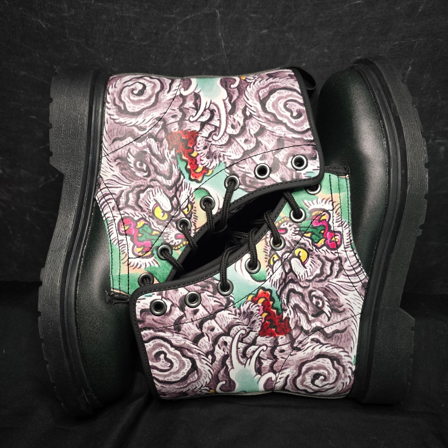 Black boots with a colorful, patterned design on a dark background